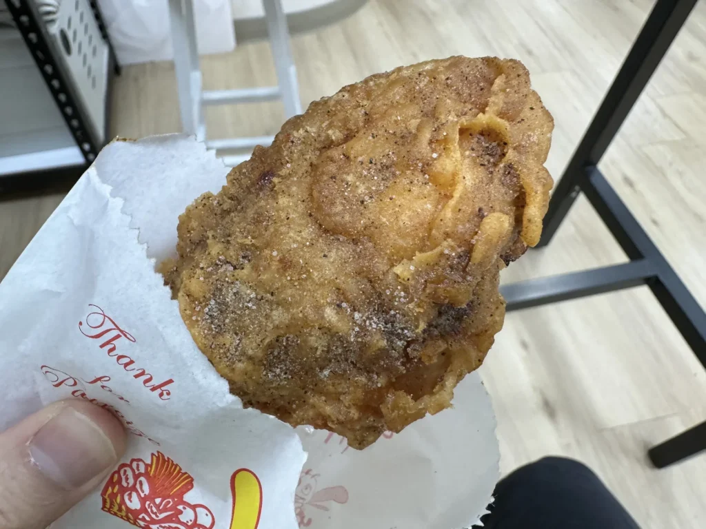 手拿著雙連轉角炸雞的脆皮雞腿，外皮金黃酥脆