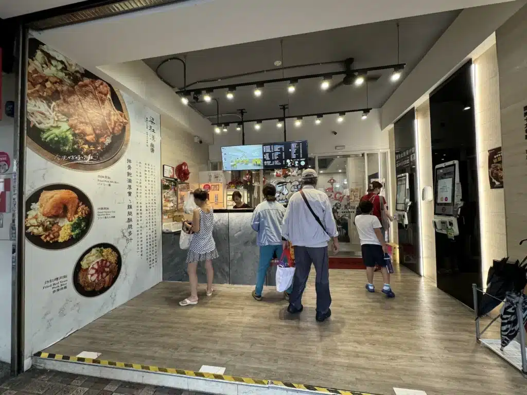 梁社漢排骨的店面內部,牆上有菜色照片、客人正在排隊點餐