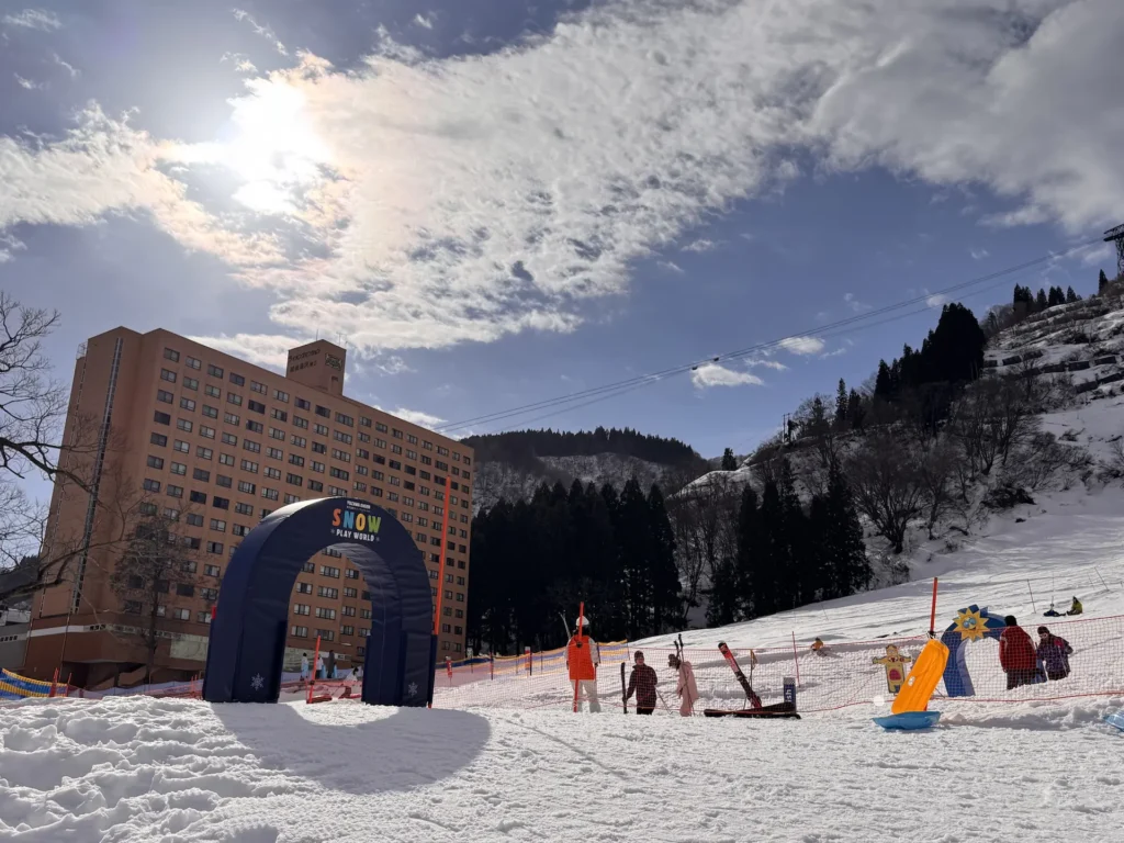 湯澤溫泉雪上遊樂園入口與滑雪場景,背景為飯店與山坡雪景