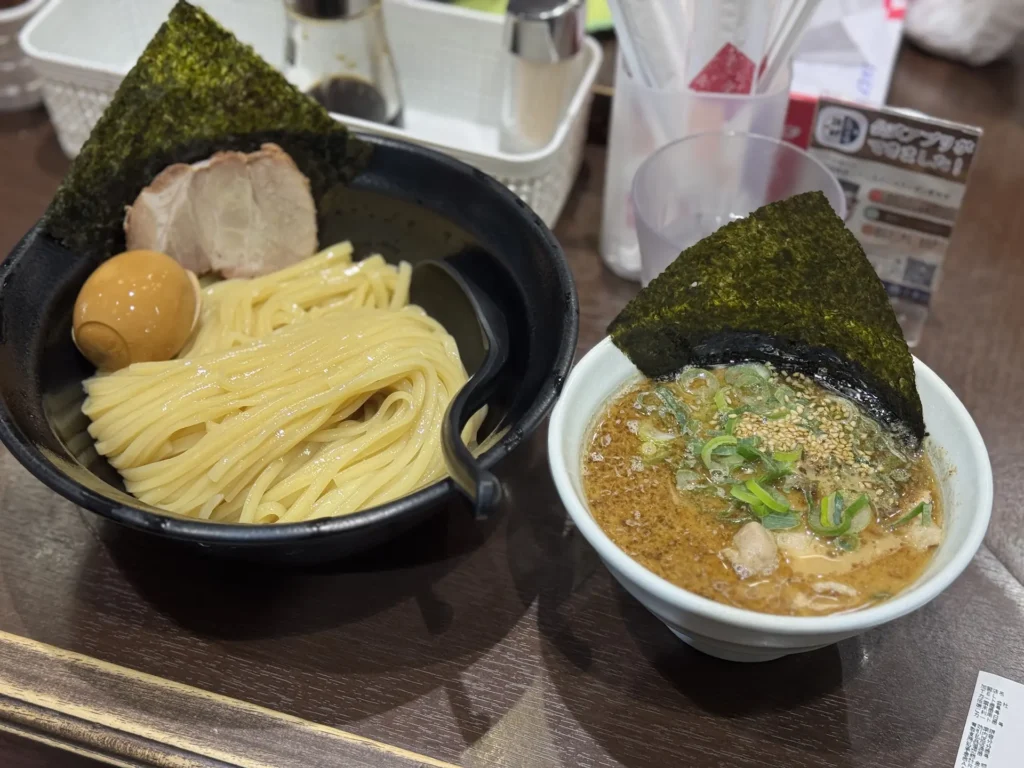 一份日式沾麵，左側為粗麵條與叉燒、海苔與蛋，右側是熱騰騰的沾麵湯汁。
