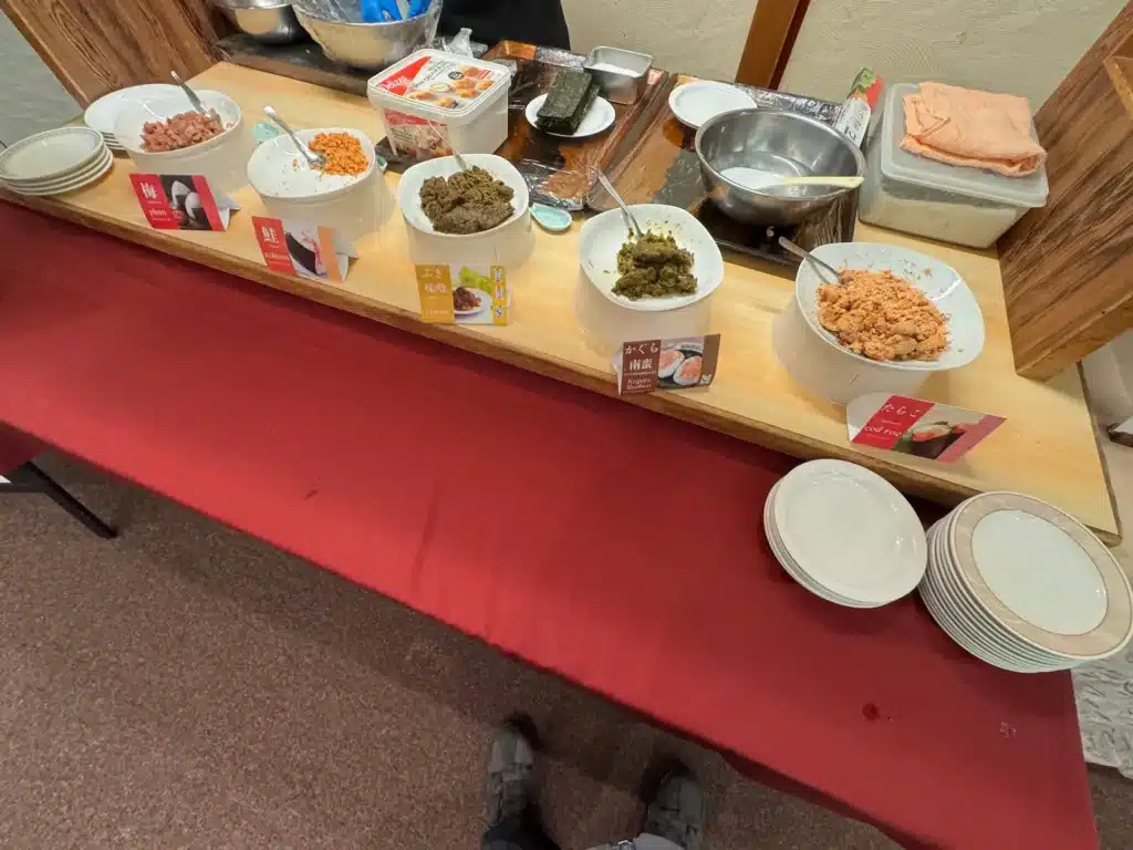 飯店飯糰製作區，提供梅子、鮭魚、ふき味噌、かぐら南蠻與明太子等多種飯糰餡料，供旅客自行組合。