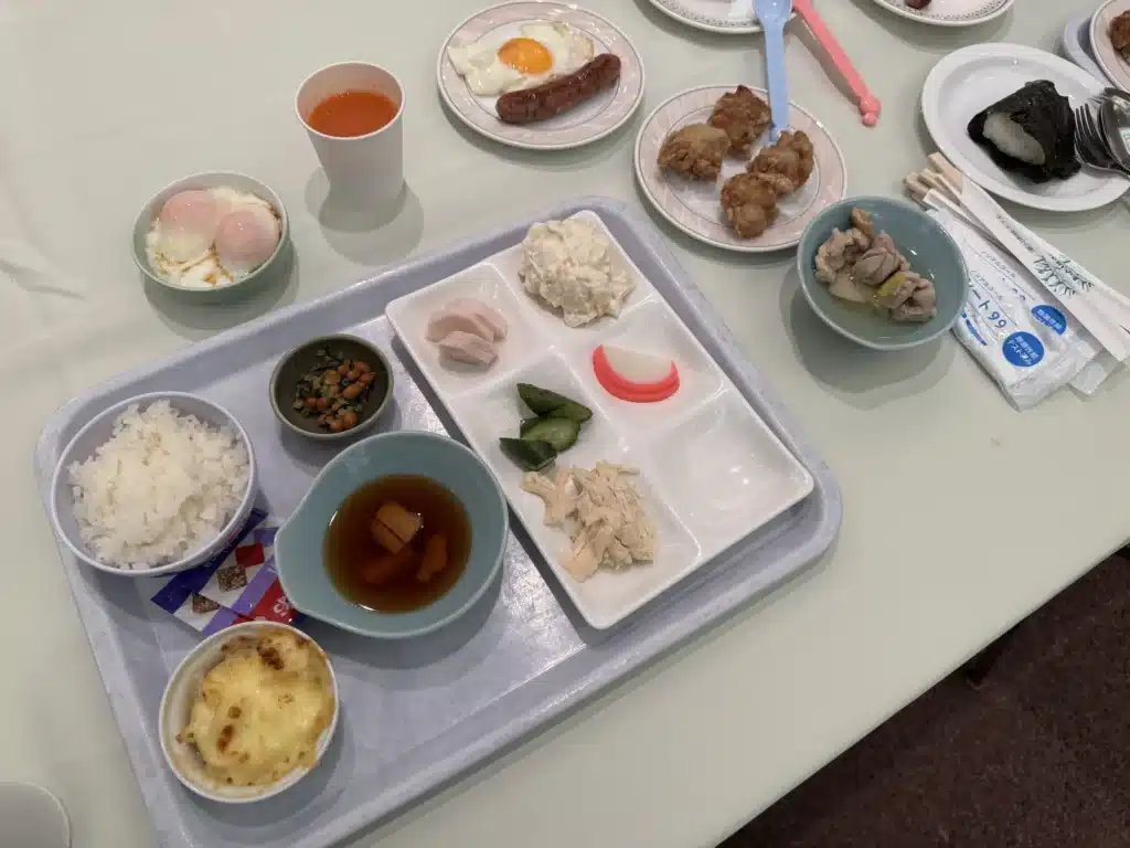 旅客在湯澤東映飯店早餐桌上擺滿各式料理，包括白飯、納豆、溫泉蛋、馬鈴薯沙拉、通心粉焗烤、漬菜以及雞肉湯品。