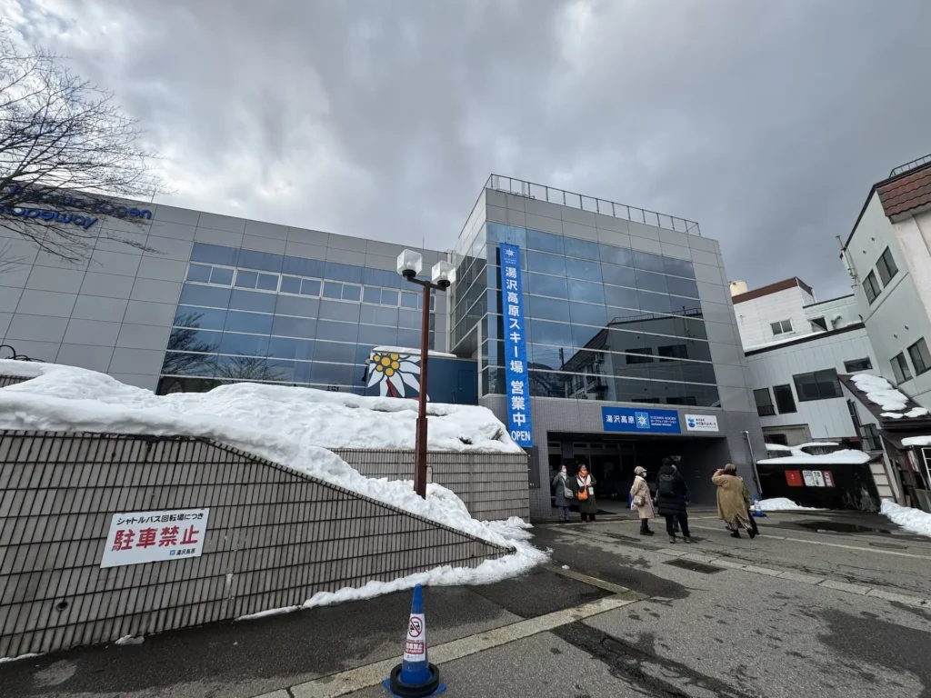 湯澤中里雪場的纜車站外觀,建築前方堆著積雪,遊客正準備入場。