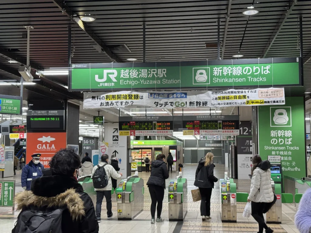 越後湯澤車站的新幹線剪票口,綠色指示牌清楚標示 Shinkansen Tracks,旅客陸續進站。