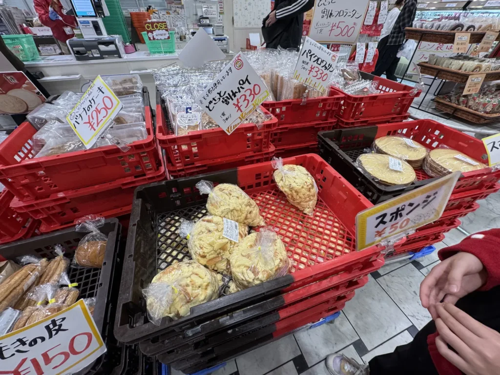 Domremy Outlet 店內貨架擺滿大量特價糕點,包括蛋糕邊、派皮、海綿蛋糕等,價格多為 150~330 日圓。