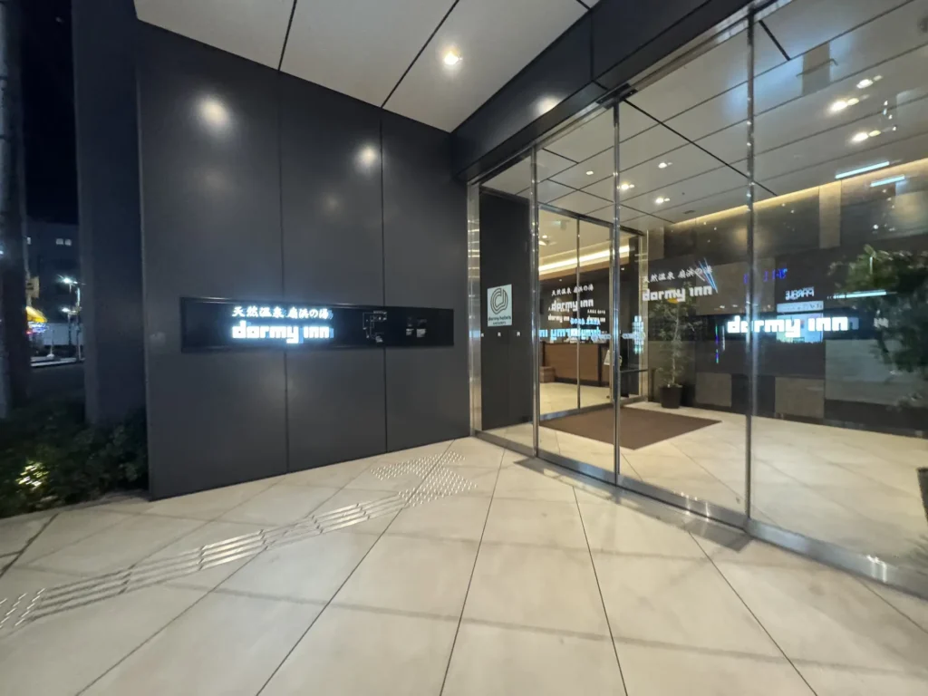 Dormy Inn 飯店入口夜景,玻璃門與發光招牌