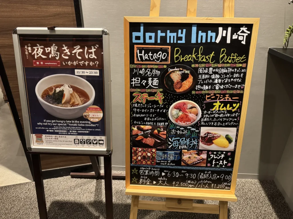 Dormy Inn 川崎館內夜鳴拉麵與早餐自助餐的告示看板,左側為夜鳴拉麵供應時間,右側為早餐菜色介紹