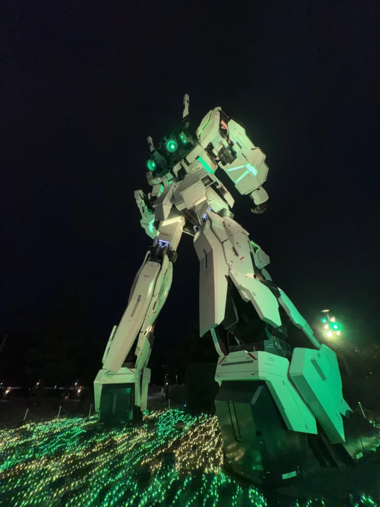 台場獨角獸鋼彈立像夜間點燈,機體上有綠色光效與地面燈海