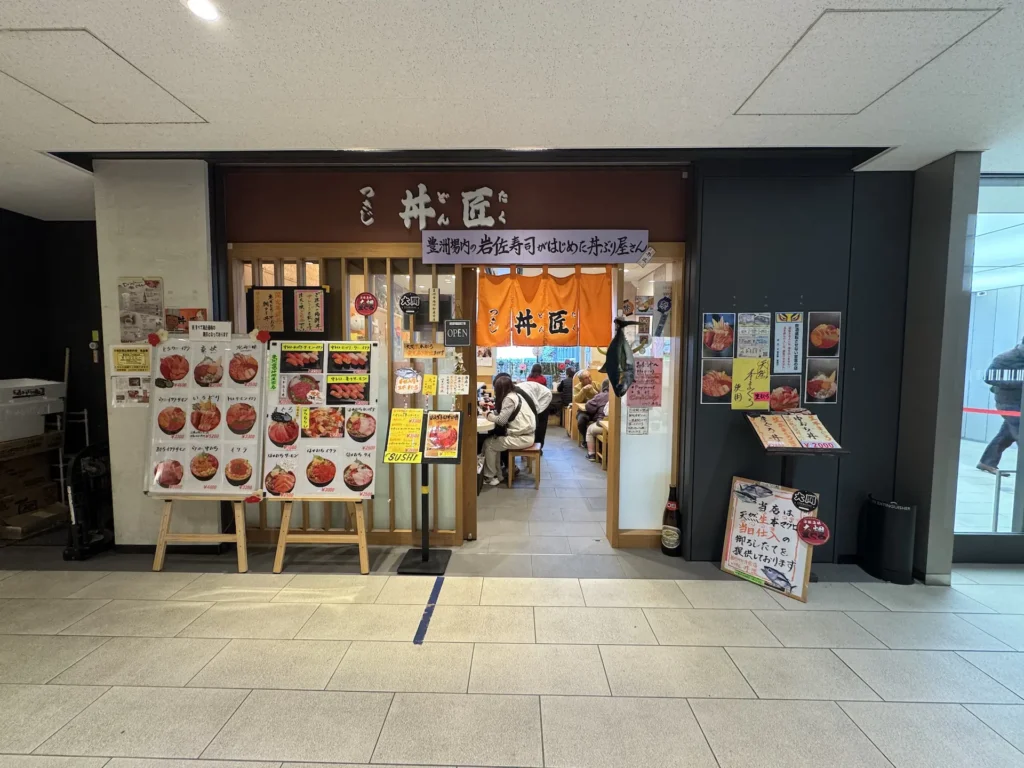 豐洲市場的丼匠店面外觀,入口前展示各式海鮮丼飯菜單。