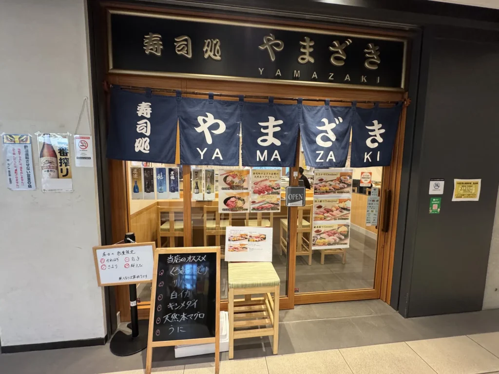 壽司處やまざき店面外觀,藍色布簾與店家推薦手寫黑板。