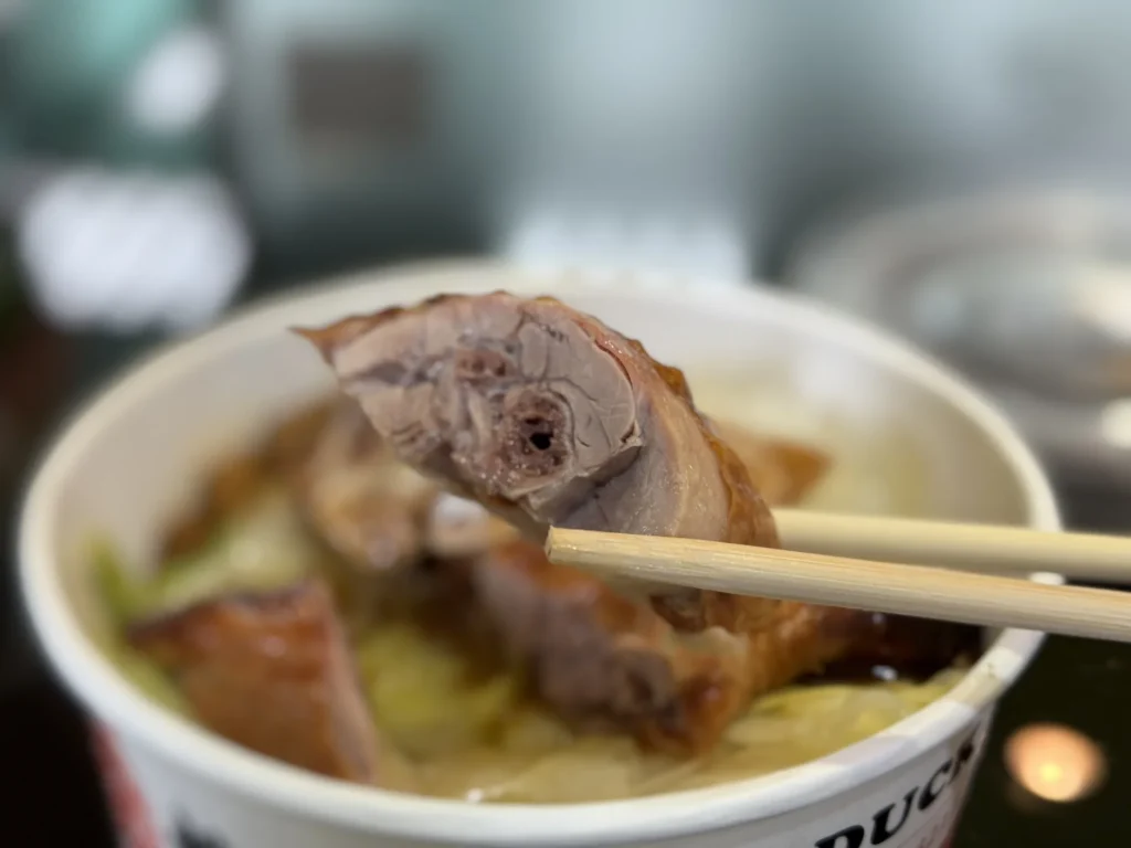 筷子夾起 1+1 燒臘烤鴨腿飯的一塊鴨腿肉