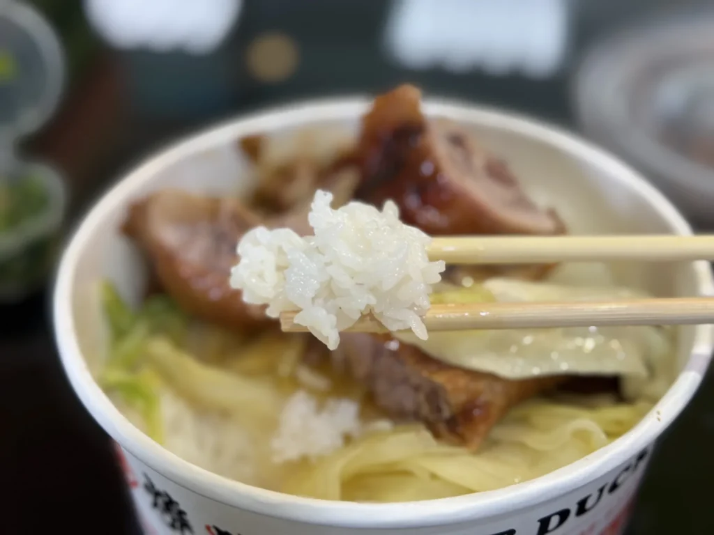 筷子夾起 1+1 燒臘便當的白飯