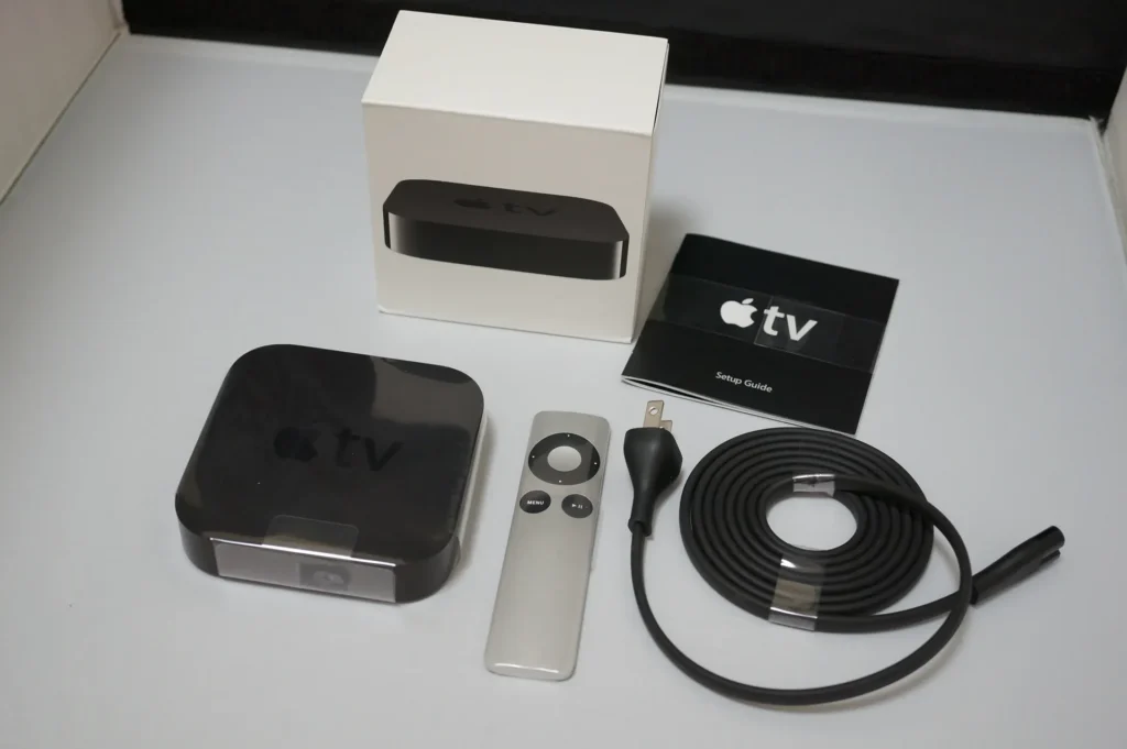 Apple TV 盒裝內容物：本體、鋁製遙控器、電源線與說明文件