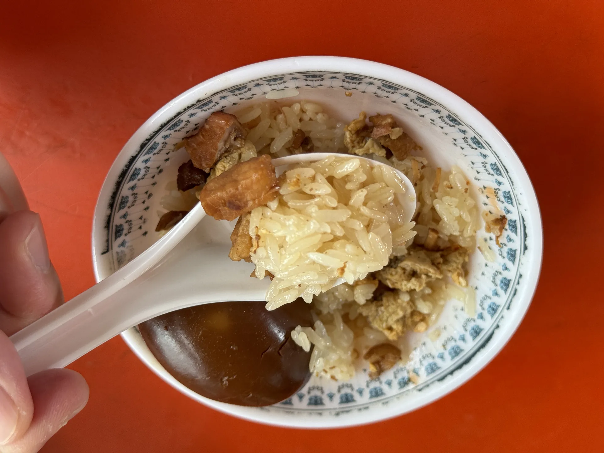 老等油飯的油飯用湯匙舀起，滷汁裹著白飯與滷肉