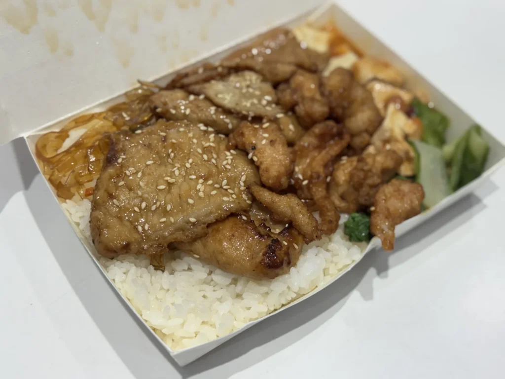 大無敵烤肉飯便當,白飯上鋪著撒了芝麻的烤肉片和雞軟骨