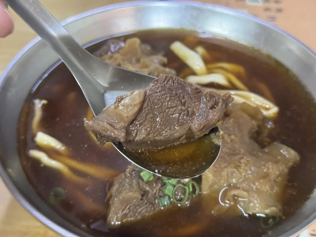湯匙舀起老熊牛肉麵的一大塊牛肉