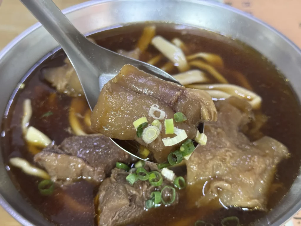 湯匙舀起老熊牛肉麵的一大塊牛筋