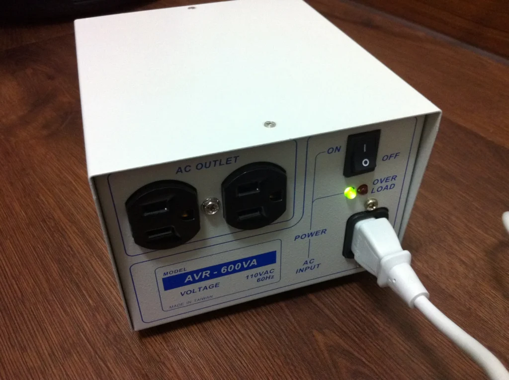 LOKO AVR-600VA 穩壓器背面，2 個三孔插座、開關與亮起的綠色電源燈