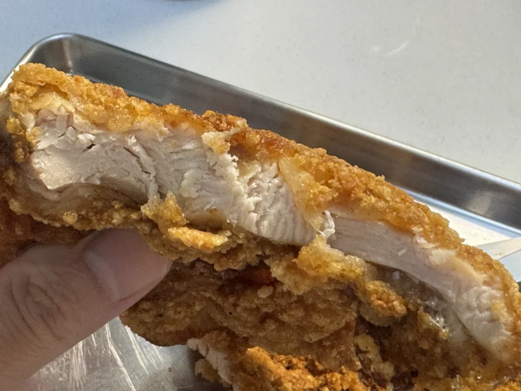 南機場好吃炸雞雞排斷面近拍，雞肉厚度是麵衣的好幾倍，肉質纖維濕潤