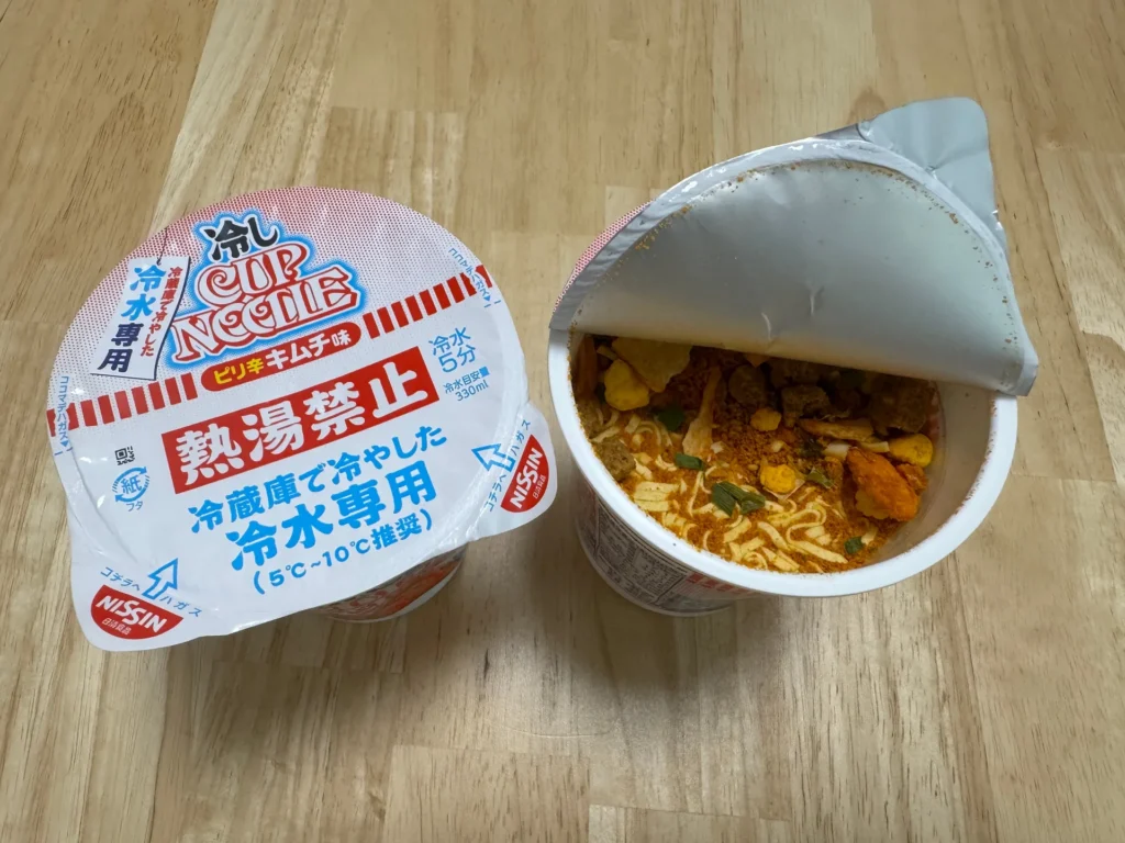 日清冷水泡麵兩杯,一杯撕開蓋子露出乾燥的麵和配料
