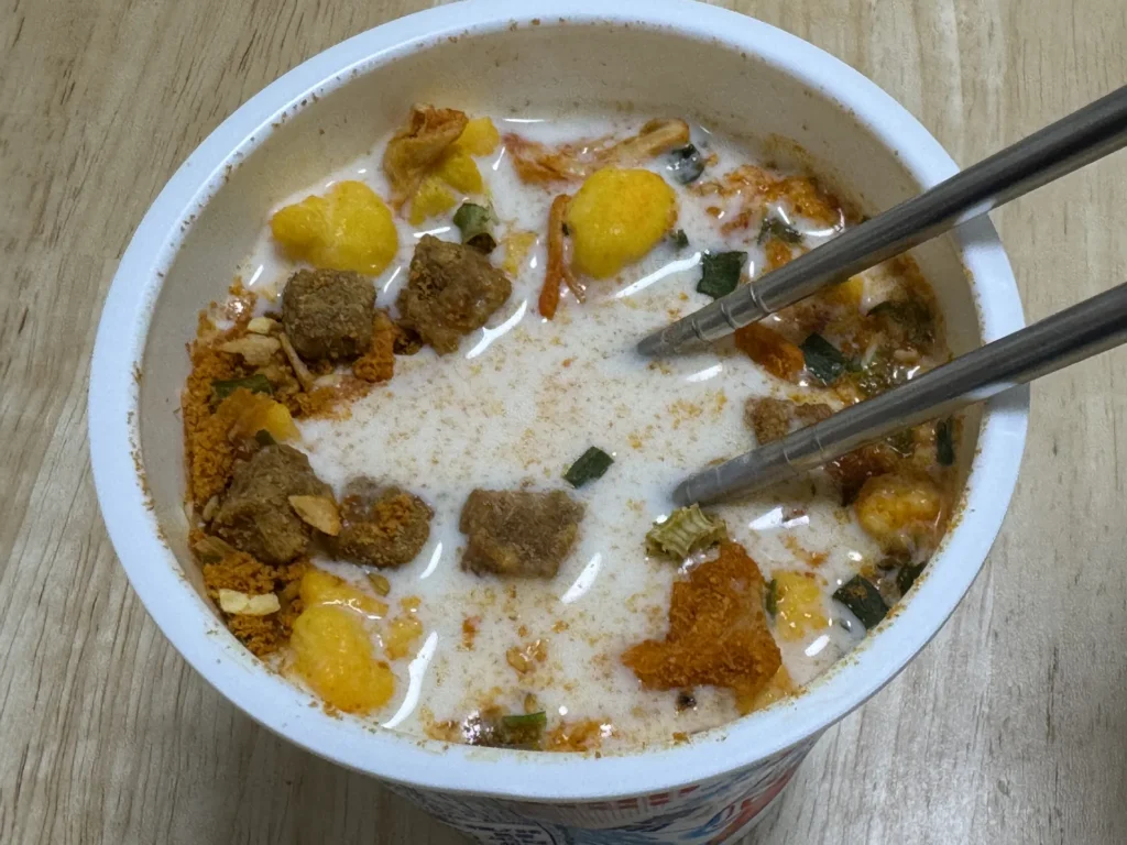 日清冷水泡麵倒入牛奶,謎肉、蛋和湯粉浮在牛奶上