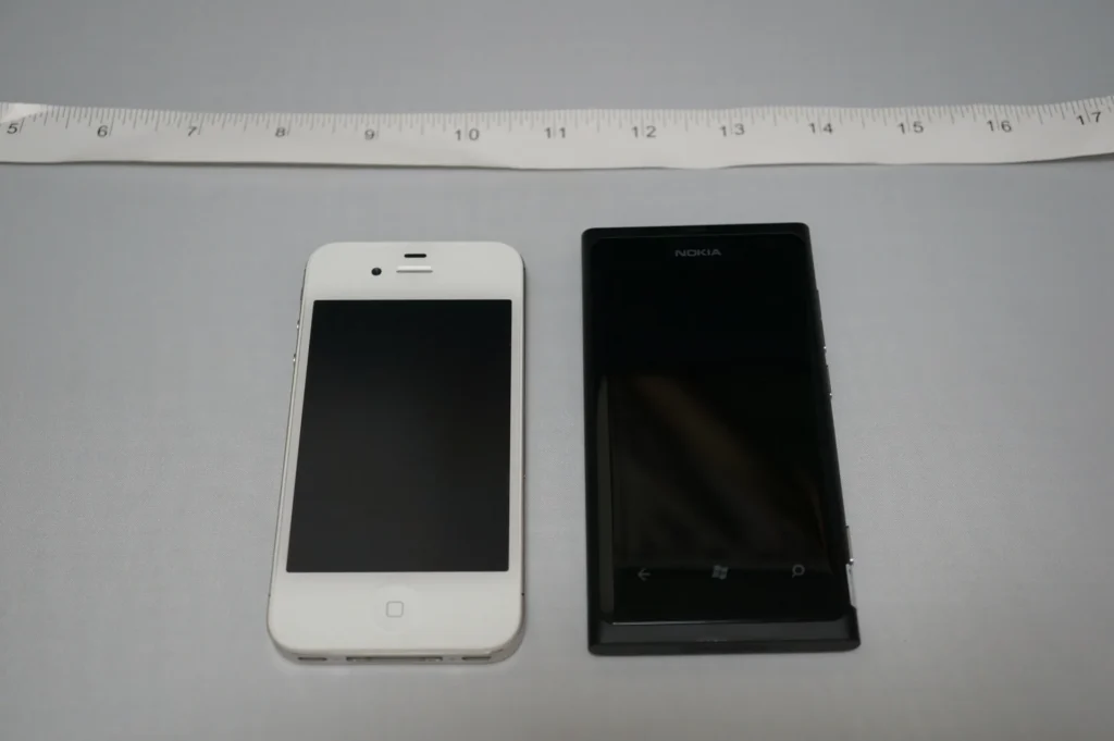 Nokia Lumia 800 與白色 iPhone 並排放在尺上比大小