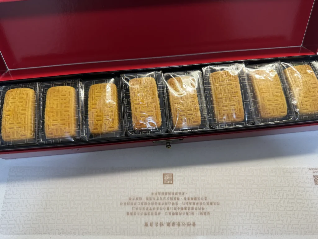 晶華鳳梨澄沙奶黃禮盒內 8 顆獨立包裝的鳳梨酥,整齊放在黑色托盤上