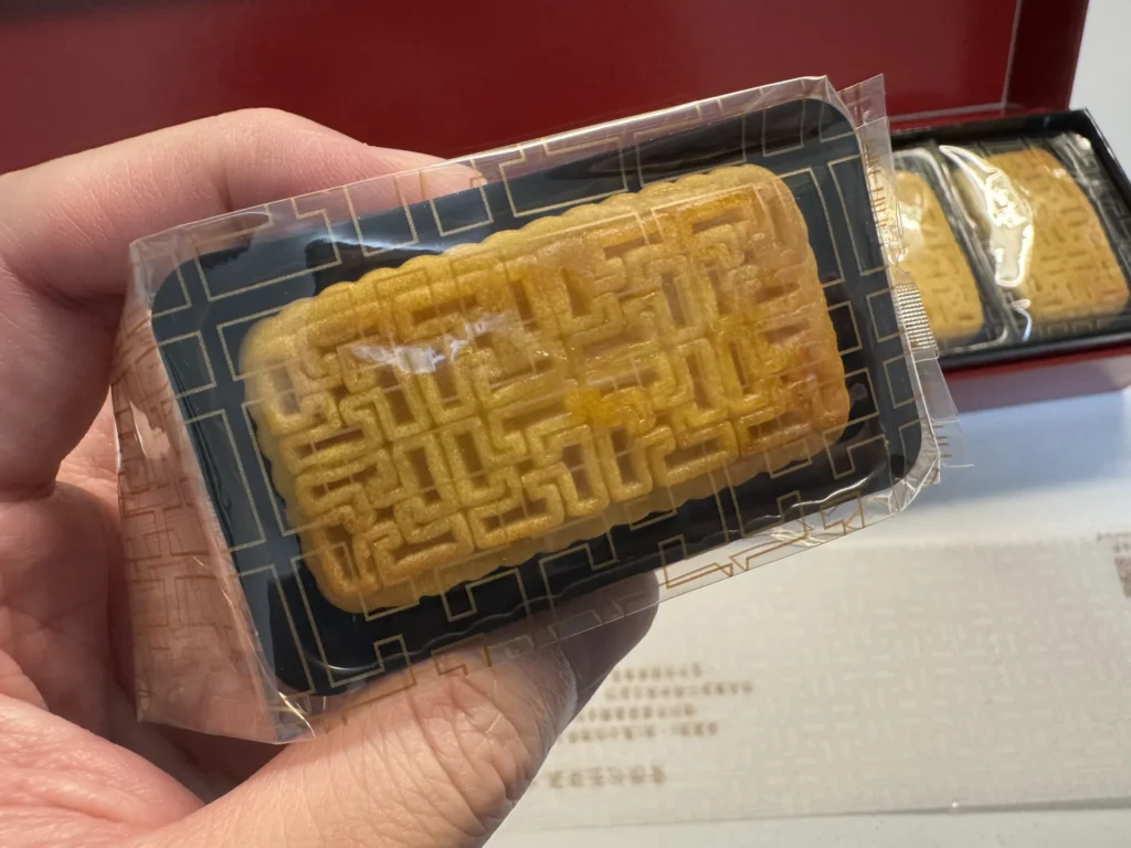 手拿一顆晶華鳳梨酥,長方形餅身表面有陰刻的幾何紋路