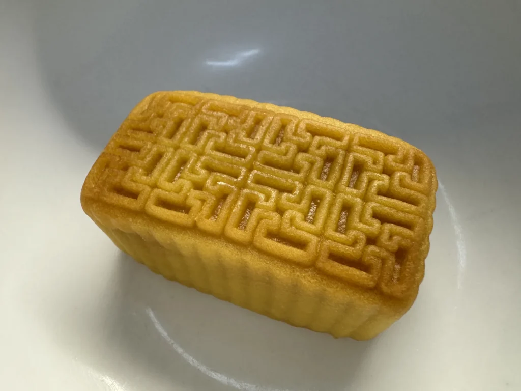 拆開包裝的晶華鳳梨酥放在白色盤子上,表面的陰刻圖案清楚可見