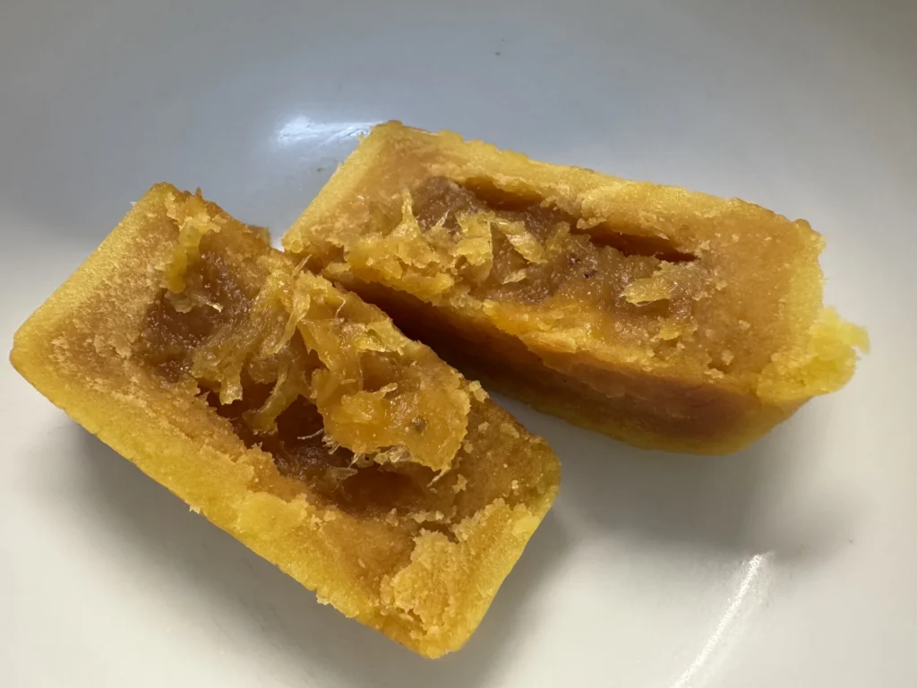 晶華鳳梨澄沙奶黃切開的剖面,外層淡黃色綿密餡包著中間金黃色的鳳梨餡