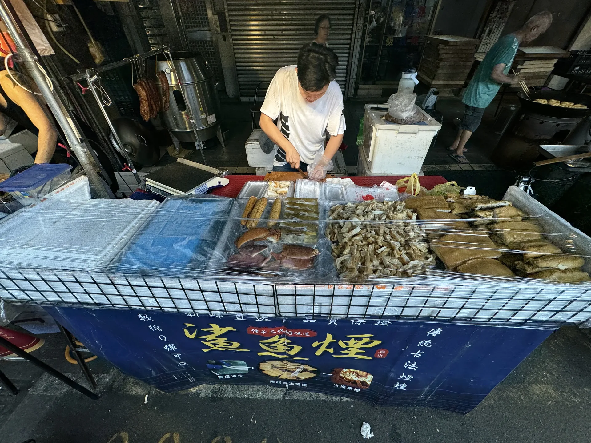 鯊魚煙攤老闆正在砧板上現切煙燻鯊魚