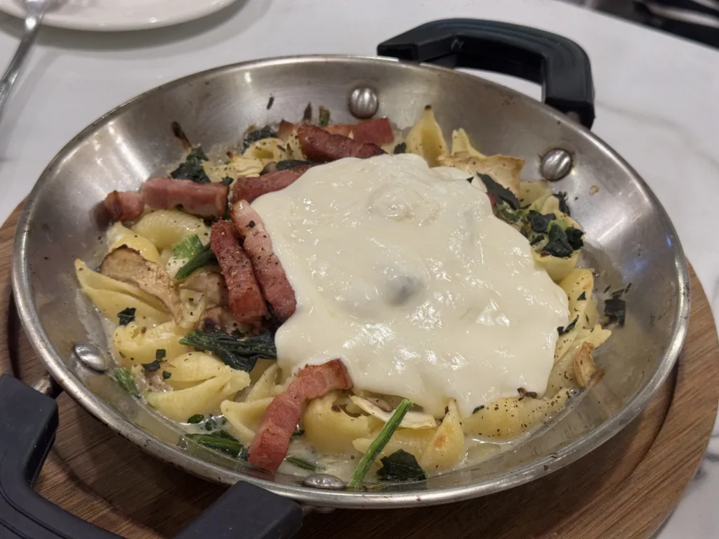 Tino's Pizza 的奶油起司瀑布烤麵,貝殼麵上蓋滿白色起司醬、培根與菠菜