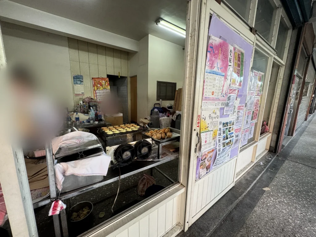 楊家紅豆餅的店面,騎樓下的烤台與貼滿海報的玻璃窗