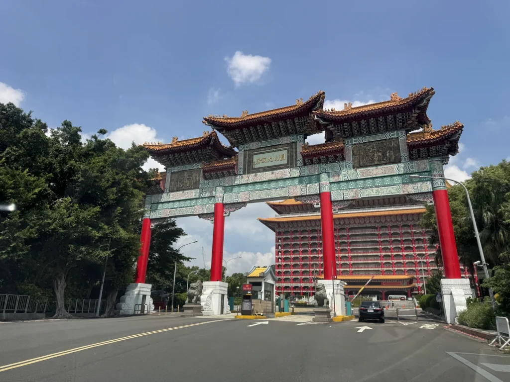 圓山大飯店紅色牌樓與後方宮殿式建築,藍天白雲