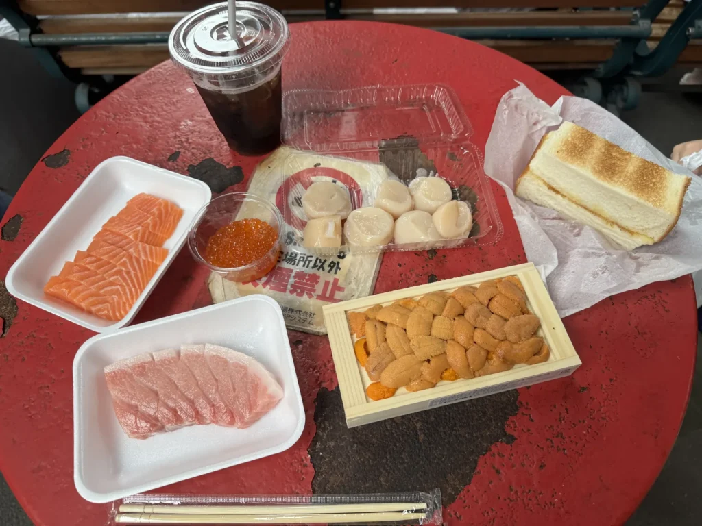 木津市場的紅色桌子上擺著鮪魚、鮭魚、鮭魚卵、海膽、貝柱和一片烤奶油麵包