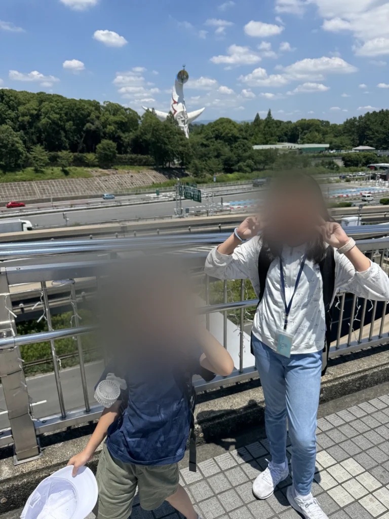 去 NIFREL 的路上,萬博紀念公園站外的天橋,遠處看得到太陽之塔,姐姐和弟弟在比 YA