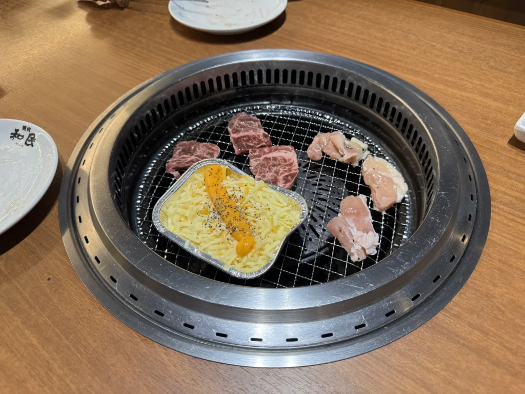 燒肉的和民的烤網上，烤著肉片和一盒起司