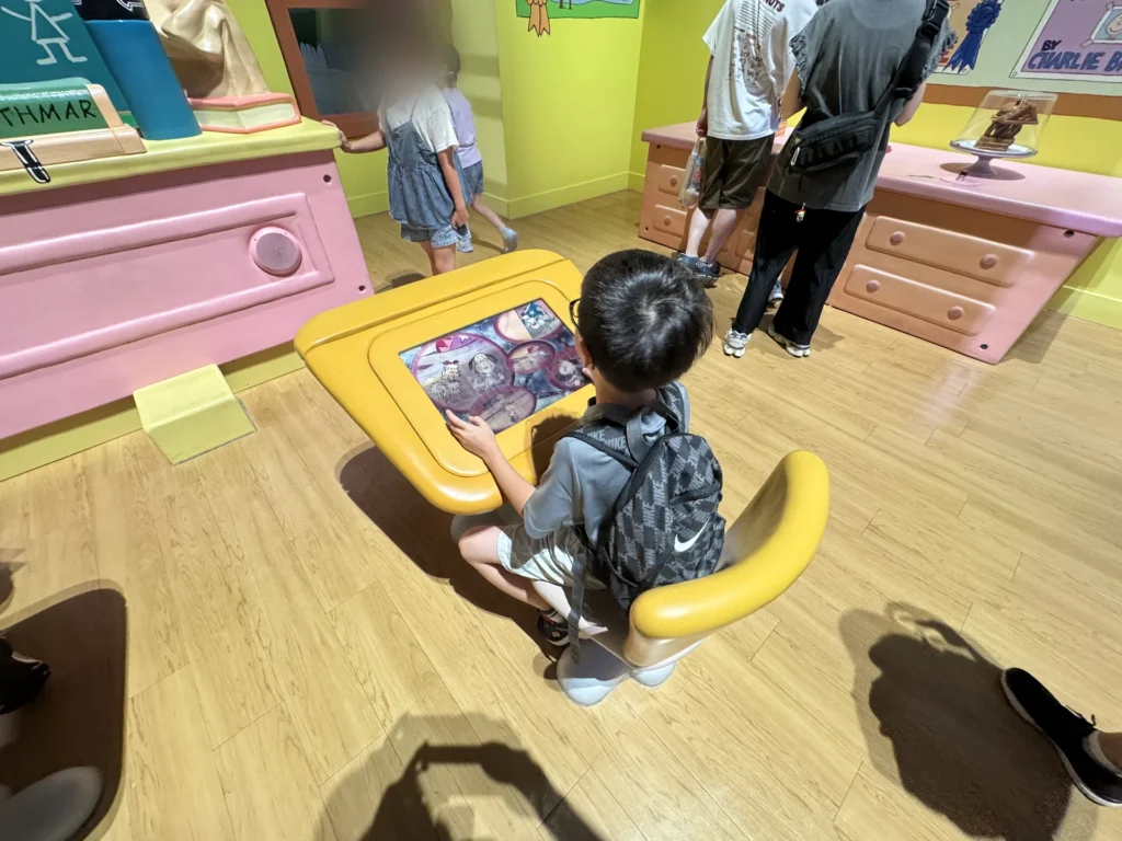環球影城史努比專區裡，弟弟坐在桌前玩觸控螢幕