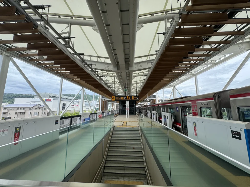 勝尾寺交通的起點箕面萱野站,月台上電車停在旁邊,中間是往下的電扶梯