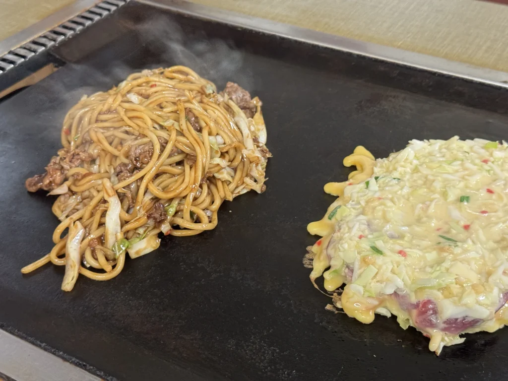 鐵板上同時煎著牛肉炒麵和大阪燒