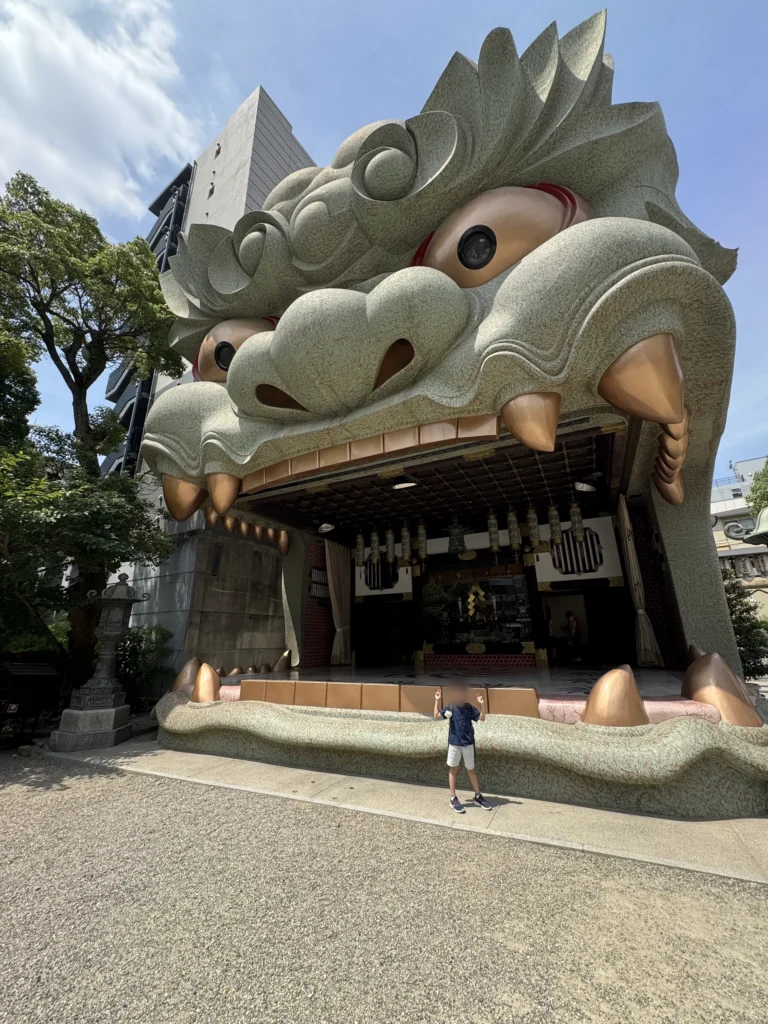 難波八阪神社獅子殿的正面，巨大的獅子頭張開嘴巴，弟弟站在前面