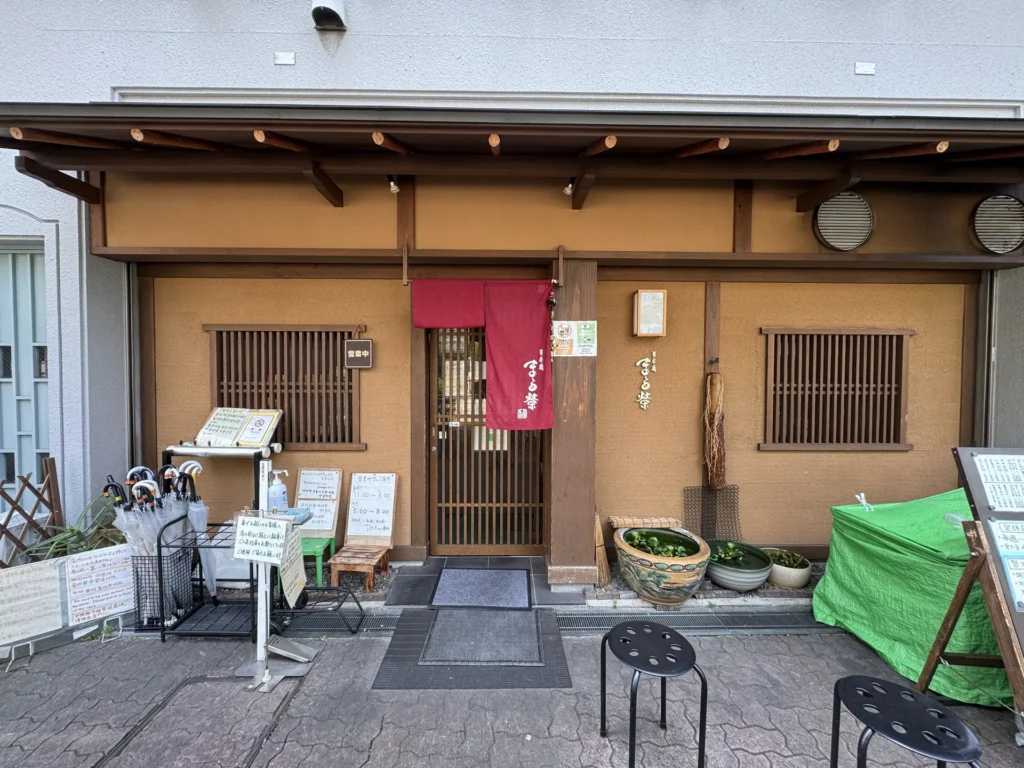 日本橋 まる榮的店門口，木頭外觀和紅色門簾