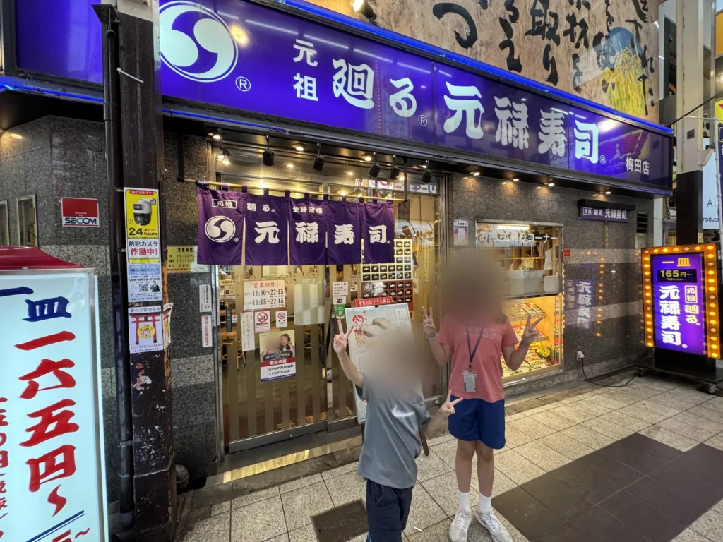 元禄壽司梅田店的門口,紫色招牌寫著元祖廻る元禄寿司