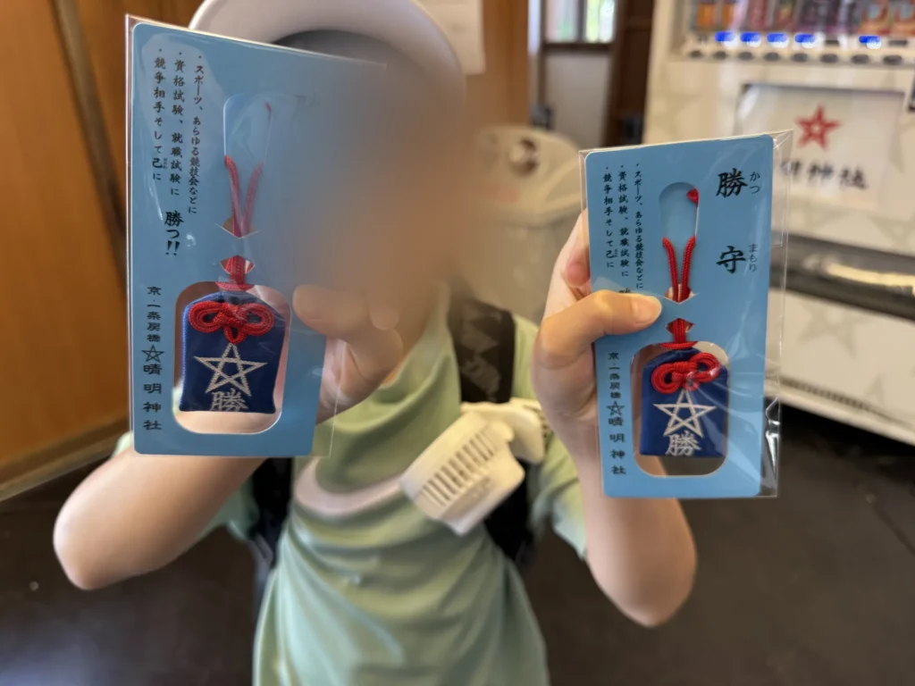 弟弟拿著兩個晴明神社的勝守，藍色御守上繡著星星和「勝」字