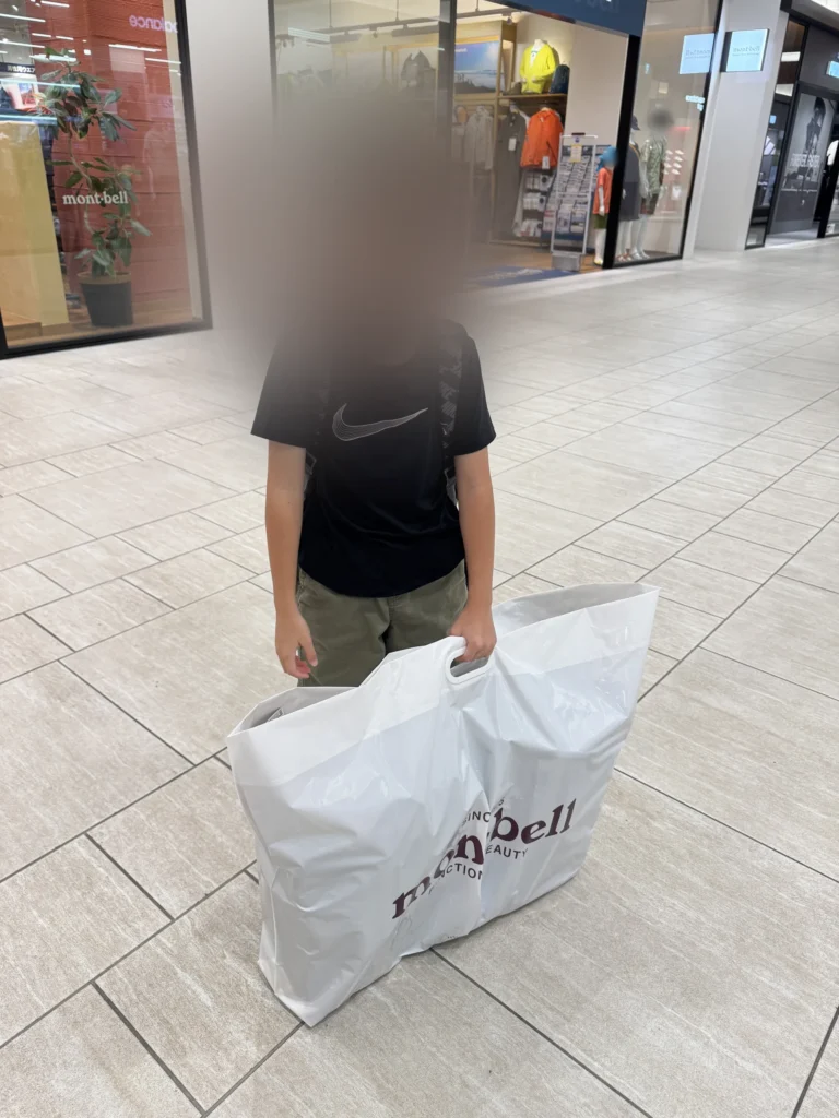 弟弟提著 mont-bell 的大袋子站在 Outlet 裡