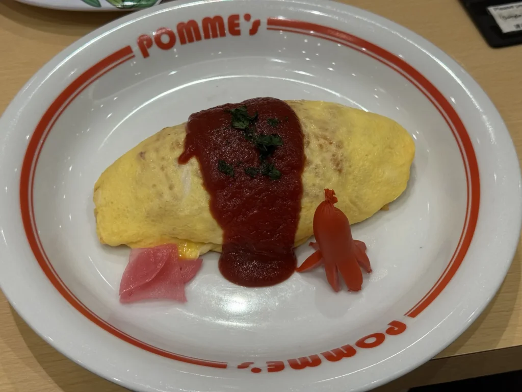 盤子上印著 POMME'S 的蛋包飯,淋著番茄醬汁