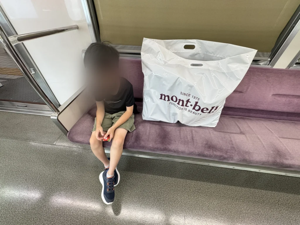 電車上,弟弟旁邊放著 mont-bell 的大袋子