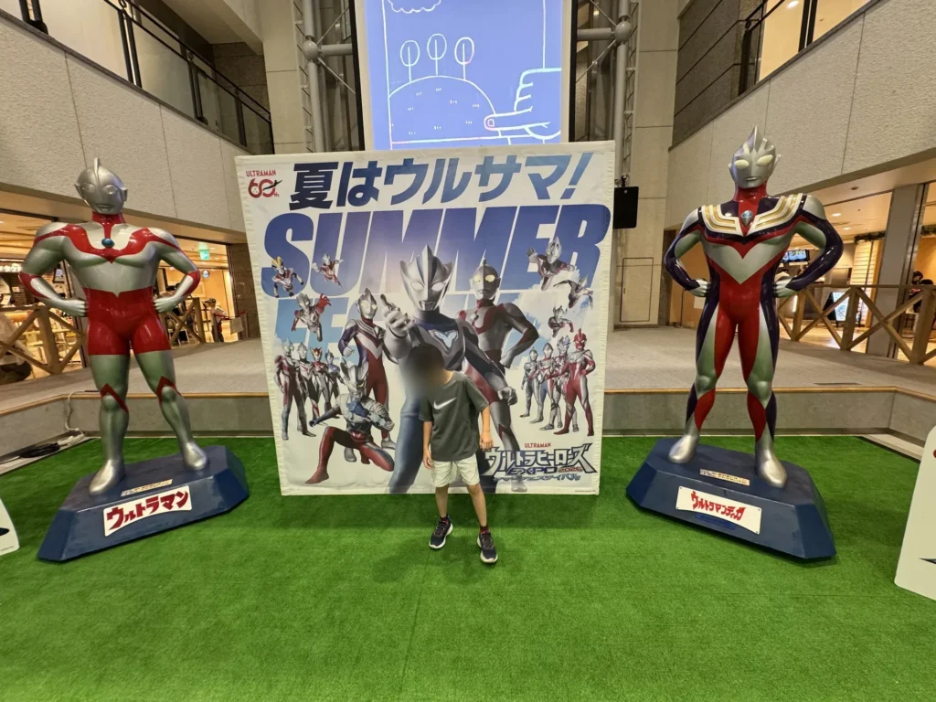 梅田的鹹蛋超人 60 週年「夏はウルサマ!」展示,弟弟站在兩尊鹹蛋超人中間