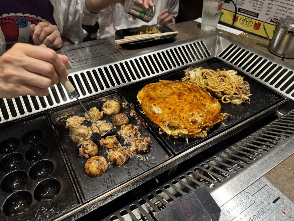 鐵板上一邊烤章魚燒,一邊煎大阪燒和炒麵