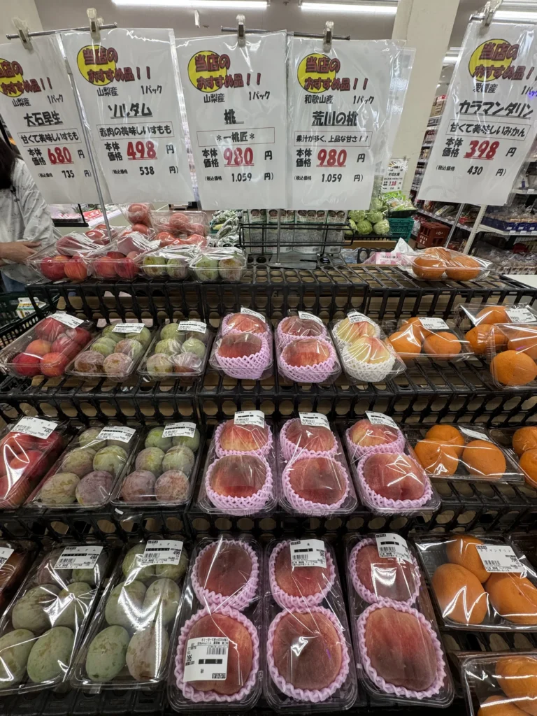 日本超市的水果架，水蜜桃和哈密瓜都套著粉紅色的網套